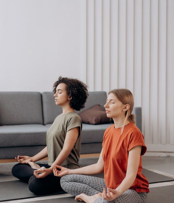 Woman in a peaceful yoga pose in a bright room with blush color accents.